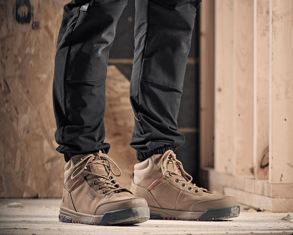 Person wearing brown Scruffs work boots and black pants in a construction setting