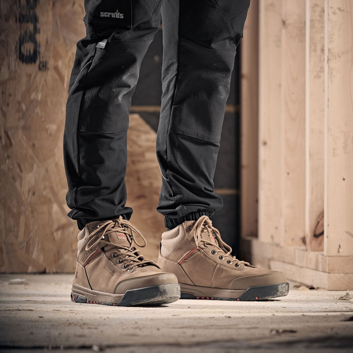 Person wearing brown Scruffs work boots and black pants in a construction setting